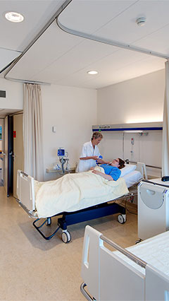 A nurse checks on her patient in a UMCG patient room, lit using Philips' energy saving lighting