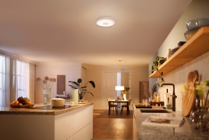 A large kitchen is illuminated with warm hues by a ceiling light and a suspended light