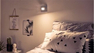 "Stylish bedroom with adjustable LED spotlight creating cozy ambiance, illuminating geometric bedding and minimalist decor."